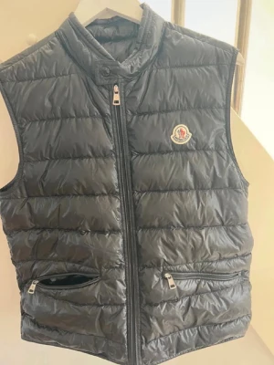 Svart dunväst från Moncler - Snygg svart dunväst från Moncler. Kvitto och påse ingår. Köpt på deras butik i Stockholm. Ny pris runt 10 000