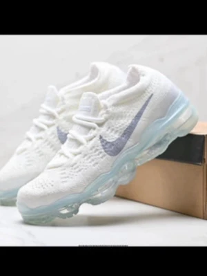 Nike Air VaporMax vita sneakers - Fräscha Nike Air VaporMax sneakers i vitt med stickad ovandel och genomskinlig, bubblig sula. Swoosh-logga i silvergrått på sidan och modern design. Perfekta för dig som gillar sportig och trendig stil.