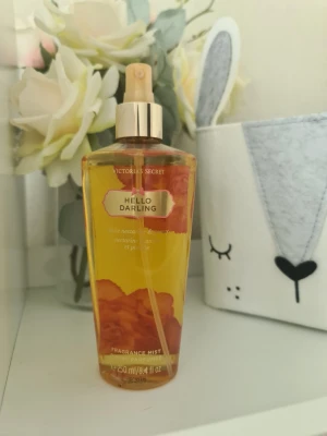 Victoria's Secret Hello Darling mist - Fräsch doftmist från Victoria's Secret i varianten Hello Darling. Flaskan är genomskinlig med guldigt spraymunstycke och detaljer, innehåller 250 ml. Doften har inslag av vit nektarin och pion. Perfekt för dig som gillar blommiga och fruktiga dofter. Helt ny och oanvänd. Säljer nu av min vintage kollektion. Perfekt för samlare. Eftersom dofterna är vintage kan lukten skilja sig markant från nya, och köps därmed på eget bevåg.