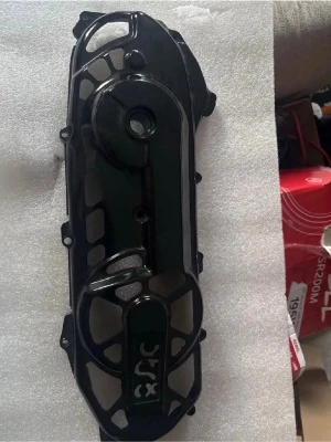 Svart variatorkåpa till moped - Säljer en svart variatorkåpa i plast till moped eller scooter. Kåpan har flera fästhål och ett mönstrat rutnät på ytan. Passar till variatorn och skyddar mot smuts och stänk. Perfekt för dig som vill byta ut eller uppgradera din mopeddel.