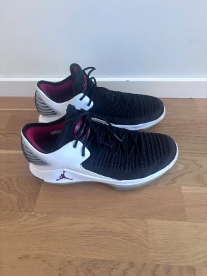 Svart/vita Air Jordan sneakers storlek 42 - Snygga Air Jordan sneakers med svart ovandel i textil och vita detaljer i läder. Skorna har en röd insida. Sulan är vit med grå och röda inslag. 