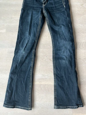Mörkblå bootcut jeans Gina Tricot - Snygga mörkblå bootcut jeans från Gina Tricot med kontrasterande vita sömmar. Klassisk femficksmodell och låg midja. Perfekta för dig som gillar en avslappnad och trendig stil. Materialet är klassisk denim.
