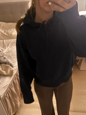 Mörkblå mysig hoodie med huva - En enkel och stilren mörkblå hoodie med huva och dragsko. Hoodien har en avslappnad passform och långa ärmar, perfekt för chill dagar. Materialet ser mjukt och bekvämt ut, perfekt att slänga på sig när man vill vara bekväm men ändå se snygg ut.