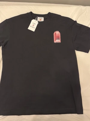 Svart t-shirt från Casablanca - Svart t-shirt från Casablanca med stor grafisk print i rosa och vitt på ryggen och mindre tryck på bröstet. Klassisk passform med rund hals och korta ärmar. Perfekt för dig som gillar stilrena men ändå unika plagg.
