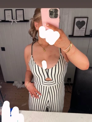 Randig klänning från Stradivarius - Snygg ärmlös byxdress från Stradivarius i svart och vitt randigt mönster. Perfekt för en stilren look med smala axelband och en figurnära passform. (Dom är kortare i benen men ska vara så)