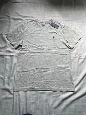 Ralph lauren T-shirt grå strl L - Helt ny Ralph Lauren T-shirt i grå färg säljes. Stilrent och enkelt basplagg med klassisk passform. Perfekt till vardag och sommar. Oanvänd i storlek L snabb frakt 