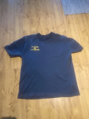 Mörkblå t-shirt - Snygg mörkblå t-shirt med trycket 'D'ONCE DE LA SENSE' i gult på bröstet. Klassisk passform och rund halsringning, perfekt för en avslappnad stil. Tillverkad i mjuk bomull för skön komfort. Kan användas upp till M beroende på hur man vill att den ska sitta! Nypris va 500