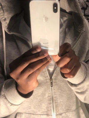 Vit iPhone X med glasbaksida - Säljer en vit iPhone X från Apple med stilren glasbaksida och rundade kanter. Mobilen har en stor skärm och en kamera placerad i övre hörnet på baksidan. Perfekt för dig som gillar snygg design och smarta funktioner.