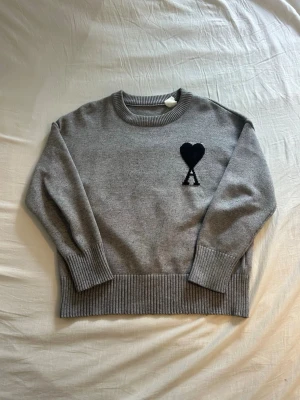 Grå Ami Paris tröja  - Grå Sticksd ami Paris tröja med svart logga. Tröjan är i storlek S och sitter skönt. Tröjan är i väldigt bra skick. Skriv vid intresse!