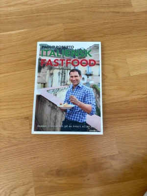 Italiensk Fastfood av Paolo Roberto - Säljer boken 'Italiensk Fastfood' av Paolo Roberto. Boken har ett färgstarkt omslag med gröna och röda bokstäver, och visar en person som äter italiensk mat. Perfekt för dig som vill laga snabba italienska rätter. Mjukt omslag och modern design.