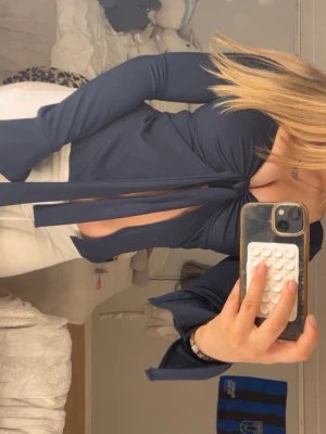 Mörkblå omlottopp med knyt - Trendig mörkblå omlottopp med långa ärmar och snygg knytning framtill. Den är nästan helt ny, bara använd ett par fåtal gånger! 💞