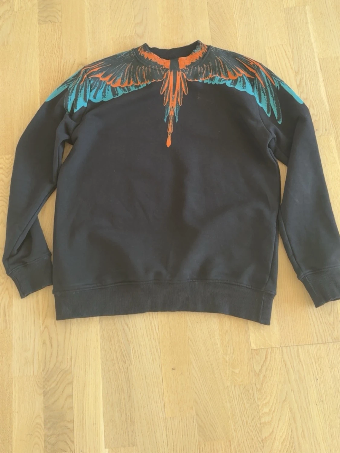Svart sweatshirt med färgglad fågel