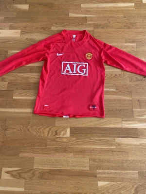 Manchester United Ronaldo tröja - Säljer en röd långärmad Manchester United matchtröja från Nike med AIG som sponsor på bröstet och Ronaldo 7 tryckt på ryggen. Tröjan har klubbmärke på bröstet och är tillverkad i ett lätt och funktionellt material, perfekt för fotbollsträning eller match.