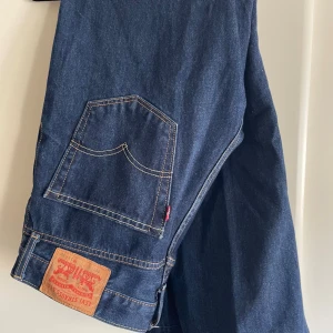 Levi's 560 blå jeans W31 L30 - Säljer ett par klassiska Levi's 560 jeans i mörkblå denim. Byxorna har raka ben, fem fickor och tydliga kontrastsömmar. Ikonisk läderpatch bak och röd Levi's-tagg på bakfickan. Perfekta för dig som gillar en avslappnad och tidlös look. Inköpta för länge sedan men knappt använda så verkligen i bra skick.