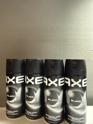 Axe Black Deospray 4-pack - Fyra flaskor Axe Black deospray med stilren svart design och vit logga. Flaskorna är cylinderformade och har en modern, matt finish. Doften är fräsch och maskulin, perfekt för dig som vill ha en diskret men ändå tydlig parfym.