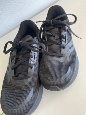 Saucony Tide 2 Triple Black sneakers - Svarta Saucony Tide 2 sneakers med mesh-överdel och syntetiska detaljer.💕 Skorna har klassisk snörning och en låg profil som ger en sportig look. Endast använd nån gång men inga syndliga tecken på användning💕Pris går att diskutera, nypris 1599🩷