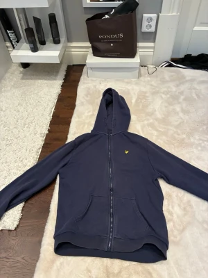 Mörkblå hoodie från Lyle & Scott - Mörkblå hoodie med dragkedja från Lyle & Scott den är 3 månader gammal säljer för att jag behöver pengar och den passar mig inte lika bra som när jag köpte den