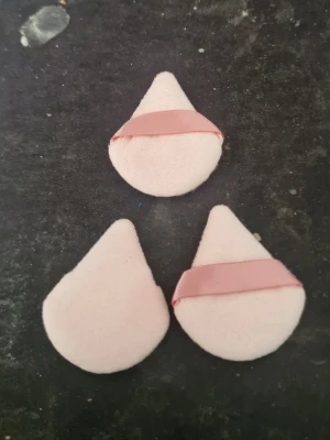 Ljusa droppformade beautyblenders - Tre ljusrosa beautyblenders i droppform med en rosa satinband på mitten för bättre grepp. Perfekta för att applicera foundation och concealer jämnt och smidigt. Materialet är mjukt och skonsamt mot huden.