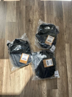 3 st the north face axelväskor  - Jag säljer 3 stycken feta unisex magväskor från The North Face. Med 3 liters kapacitet, rymligt huvudfack, justerbar rem, innerficka med nyckelkrok och innerficka i nät. Säljes på grund av felbeställning. Skriv om du bara vill köpa en. Priset är något förhandlingsbart. Modell: "Y2K SHOULDER BAG TNF BLACK-ASPHA" Storlek: one size Mått: 20 × 15 × 7 cm