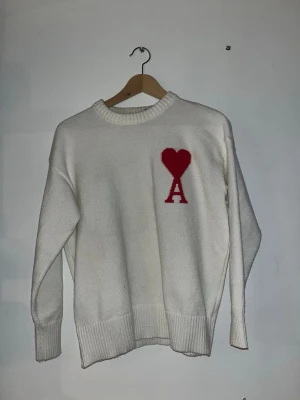 Vit stickad tröja från Ami Paris - Vit stickad tröja från Ami Paris med röd broderad logotyp på bröstet storlek S jätte fint skick 