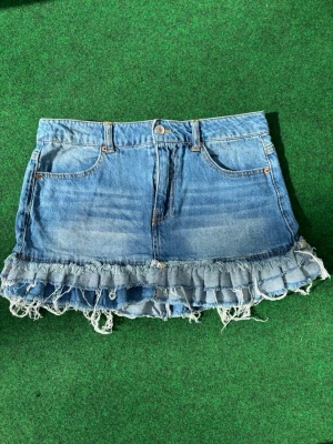 Blå jeanskjol med volang och fransar - Blå jeanskjol som är perfekt inför sommarn. Den passar till allt! Sparsamt använd  Pris kan diskuteras!💵 och måtten finns på bild VIKTIGT! 