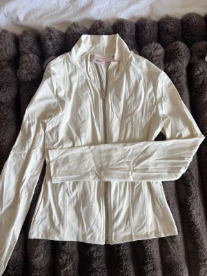 Vit zip-tröja i träningsmaterial - Snygg vit zip-tröja från ginas 14+ kollektion. Tröjan har en figurnära passform och är tillverkad i ett mjukt och stretchigt material.  Använd vid ett tillfälle 