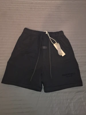 Svarta Essentials shorts med snörning - Säljer ett par svarta shorts från Essentials. Säljer dom pågrund av dom är lite för små för mig. Men annars så är dom i topp skick. Perfekt för dig som har letat efter fina och sköna shorts. Kan gör bra dill vid snab affär.