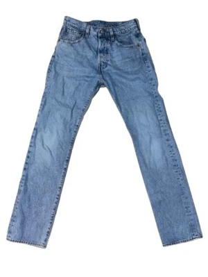 501 - Blå raka jeans Levi's - Klassiska blå jeans från Levi's med rak passform och fem fickor. Jeansen har normal midja, knappgylf och är tillverkade i slitstark denim. Perfekta för en avslappnad och tidlös stil.