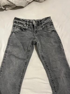 Grå jeans  - Snygga grå jeans med dragkedjegylf. Jeansen har en tvättad look och utsvängda ben. Perfekta för en avslappnad och trendig stil.