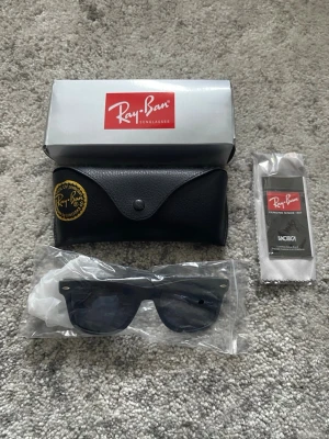Ray-Ban solglasögon  - Ett par svarta Ray-Ban solglasögon i nytt skick, oanvända. Orginalförpackning, etui med mera medföljer självklart (se bild 1). Hör gärna av er om det är nåt ni undrar!