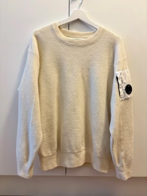 Vit sweatshirt från C.P. Company - Vit sweatshirt från C.P. Company i storlek 52, motsvarar M/L. Tröjan är i mycket bra skick och tags finns kvar.