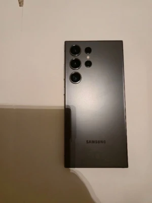 Samsung Galaxy svart Android-telefon - Snygg svart Samsung Galaxy Android-telefon med stilren design och flera stora kameralinser på baksidan. Telefonen har en matt finish och rektangulär form med rundade hörn. Tillverkad i glas och metall för en premiumkänsla. Perfekt för dig som gillar modern teknik och grym kamera.