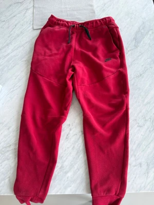 Nike tech byxor - röda nike tech mjukisar ganska använda men i bra skick lite slitna på snörena. Storlek S!