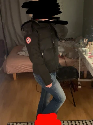 Svart dunjacka från Canada Goose - Säljer en svart äkta dunjacka från Canada Goose med klassisk patch på ärmen. Jackan har huva, dragkedja framtill och en puffig, varm design som passar perfekt för kalla vinterdagar. Snygg och tidlös modell som håller dig varm hela säsongen. 