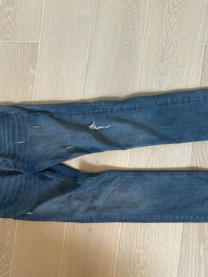 Blå slitna jesns - Säljer ett par blå jeans med slitningar ifrån Jack and Jones. Jeansen är i ett bra sick. Storlek: 30 30.