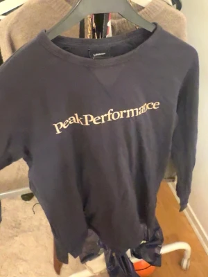 Mörkblå sweatshirt Peak Performance - Snygg mörkblå sweatshirt från Peak Performance med klassisk logga tryckt i vitt på bröstet. Tröjan har rund halsringning och långa ärmar, perfekt för en avslappnad och sportig stil. Tillverkad i mjukt bomullsmaterial.