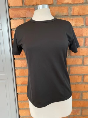 SOC Svart sport-tshirt strl 38 - En stilren svart sport-tshirt från SOC med rund hals och korta ärmar. Tillverkad i ett lätt och snabbtorkande funktionsmaterial som passar perfekt till träning och aktivitet. Diskret logga i nacken på baksidan.