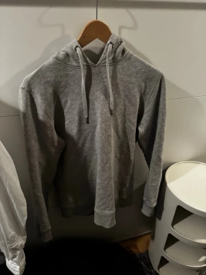 Grå hoodie från Stenströms - Snygg grå hoodie från Stenströms med klassisk huva och dragsnören. Har ett par defekter men inget som syns och går lätt o sy ihop det är storlek s och bortom defekterna är det är riktigt fet och snygg hoodie tidslös