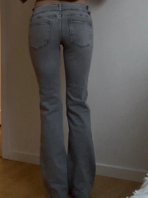 Grå bootcut jeans med söm - Säljer ett par grå bootcut jeans med markerade sömmar framtill och bakfickor. Jeansen har låg midja och vida ben, vilket ger en snygg retrovibe. Storlek 158