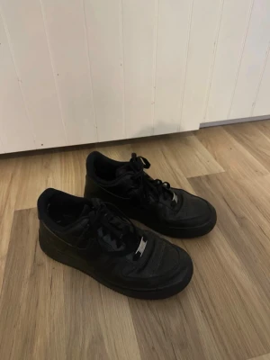 Svarta Nike Air Force 1 sneakers - Säljer ett par svarta air force skor i storlek 38,5, fint skick bara att dem är lite slitna i hälen ( finns bild). tvättar dem såklart innan jag skickar