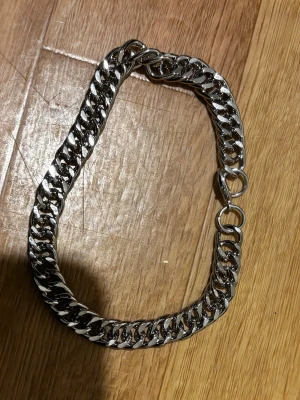 Silverfärgat kedjearmband - Stilrent armband i silverfärgad metall med breda, platta länkar. Klassisk kedjedesign som ger en cool och modern känsla. Perfekt accessoar för att lyfta din outfit med en edgy touch. Helt nytt! Säljs pga flytt!