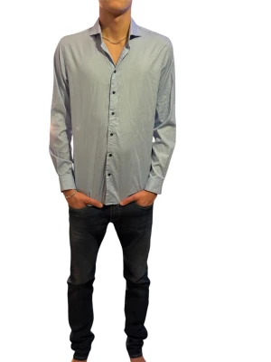 Ljusblå skjorta - Snygg ljusblå skjorta med klassisk krage och svarta knappar hela vägen framtill. Skjortan har lång ärm och en rak passform som funkar till många olika stilar. Tillverkad i ett tunt och bekvämt bomullsmaterial.