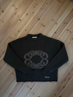 Mörkgrön stickad tröja Prohibited - Mörkgrön stickad tröja från Prohibited med ett stort, ljust mönster i form av en cirkel på bröstet. Tröjan har ribbstickad hals, muddar och nederkant samt en metallbricka med logga vid fållen. Perfekt för dig som gillar unik design och sköna material. Storlek xs men passar som S.