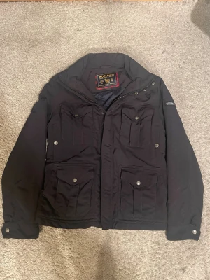  Woolrich field jacka - Hej! Säljer nu denna snygga och eftertraktade Woolrich "John Rich & Bros" Jacka! Storlek M! Nypris= 6500 kr, säljs för 1499 kr! Denna jacka är väldigt unik med sina klassiska fyrfickshon-detaljer och är väldigt svår att få tag på i detta skick!