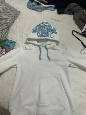 Vit Syna World Tracksuit  - Unik vit och blå syna world trsvksuit    Syna world  Hoodie Chest: 47 cm Length: 65cm Arms: 68 cm  Pants  Waist: 41 cm (stretchy) Inner leg: 78 cm Outer leg: 102 cm