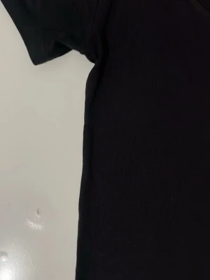 Svart t-shirt från 157 - En basic svart t-shirt från 157 med rund halsringning och korta ärmar. Tillverkad i mjuk bomull med lite stretch för extra komfort. Perfekt att matcha med jeans eller kjol för en enkel och clean look.