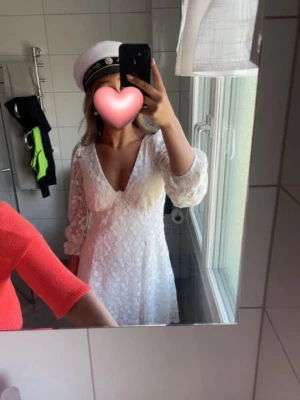 Vit klänning student  - Säljer en vit klänning med v-ringning och långa spetsärmar. Klänningen har blommigt mönster och markerad byst. Perfekt till student. Säljs inte längre.