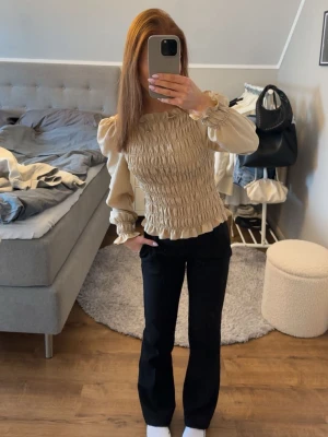 Beige smockad blus med puffärm - Trendig beige blus med smockad kropp och voluminösa puffärmar. Blusen har rund halsringning och långa ärmar med resår vid ärmslut för extra detalj. Perfekt för dig som gillar en romantisk och chic stil. Från hm, storlek xs. Jättefint skick. Hör av er vid frågor och kom gärna med prisförslag!💞