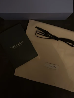 Svarta lackade sneakers från Lanvin - Snygga svarta sneakers från Lanvin med lackad finish och vita sulor. Skorna har svarta skosnören och metallfärgade öljetter. Klassisk låg modell som ger en clean och modern look. Perfekta för dig som vill sticka ut med stilrena detaljer.