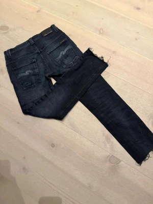 Svarta jeans från Nudie - Svarta jeans från Nudie!! Perfekta för dig som gillar en stilren och modern vibe. Snygga slitningar och se modellen och storlek på sista bilden!! Jeansen är klippt där dere så sitter dom är i mellan L 32 och 30, därav priset!! 